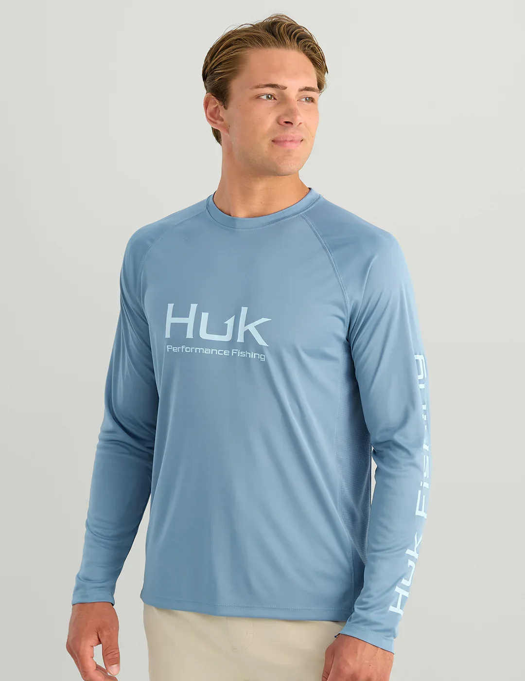 Model wearing a Huk long-sleeve performance fishing shirt