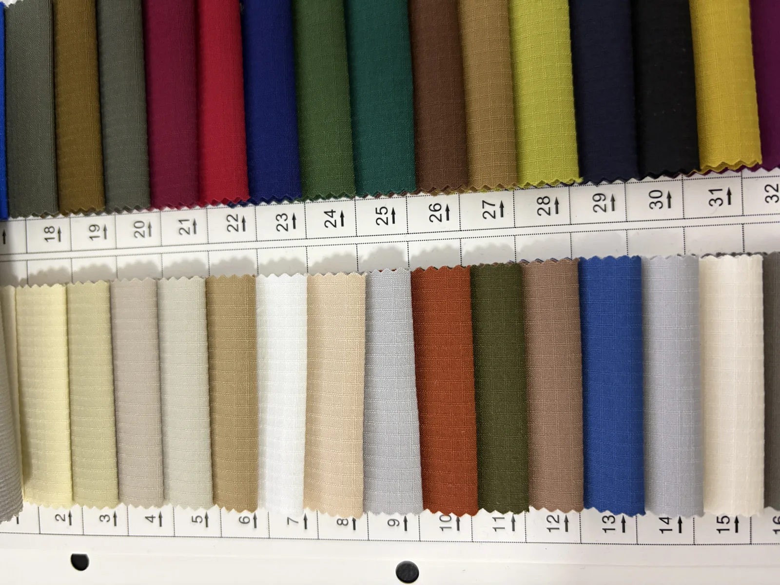 Folded ripstop fabric swatches showing light neutrals, coastal blues and outdoor colors