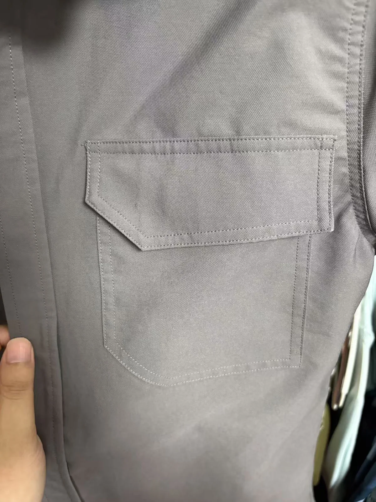 Close-up of a reinforced chest pocket and shaped flap on a gray button-up fishing shirt