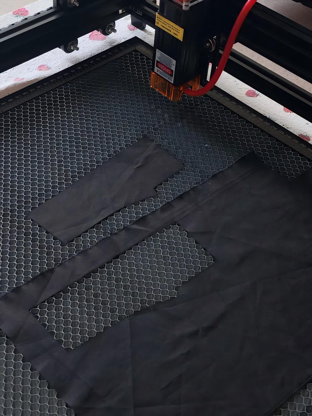 Laser cutting machine cutting fabric panels for a custom fishing hoodie