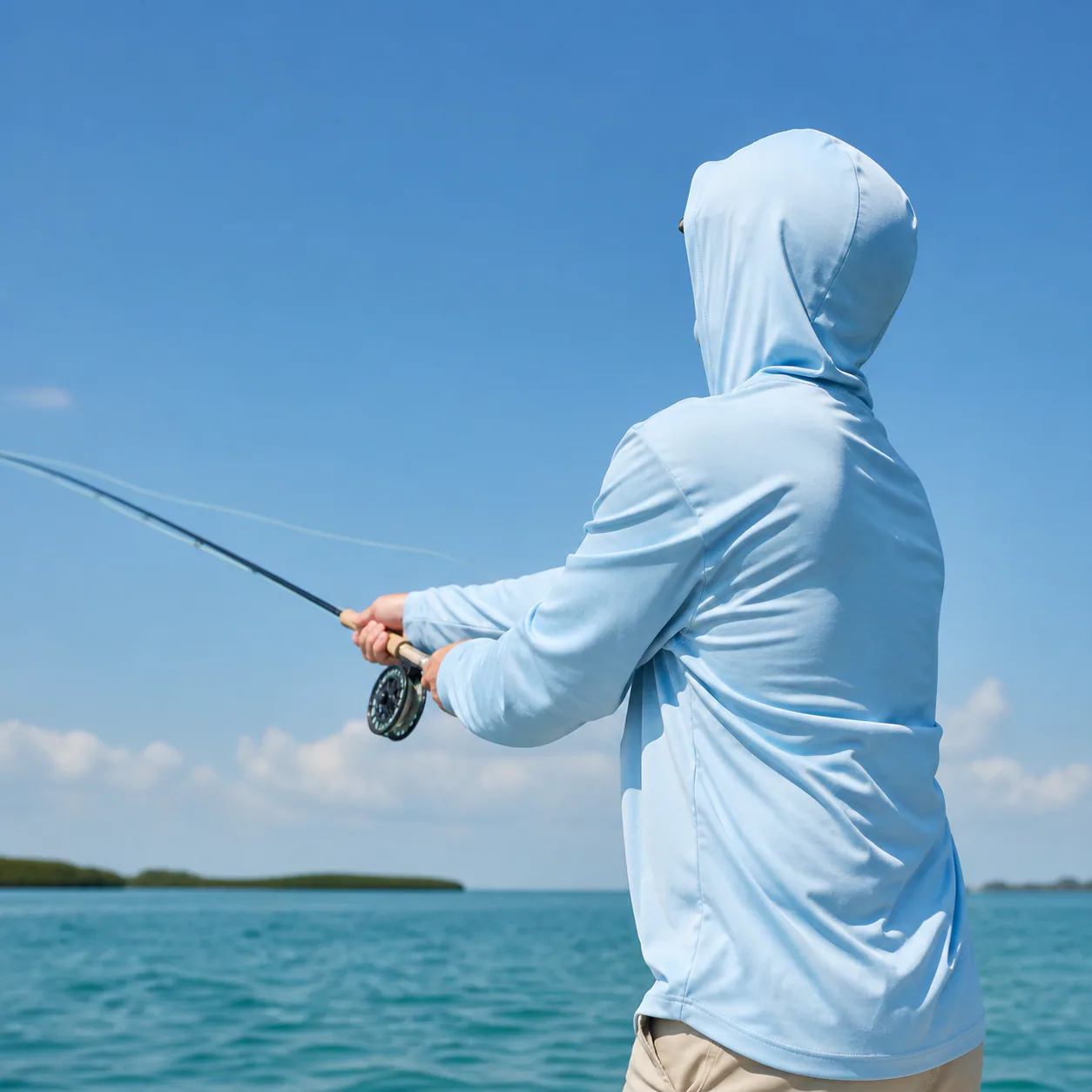 Angler wearing an unbranded light blue hooded UPF fishing shirt while casting on open water