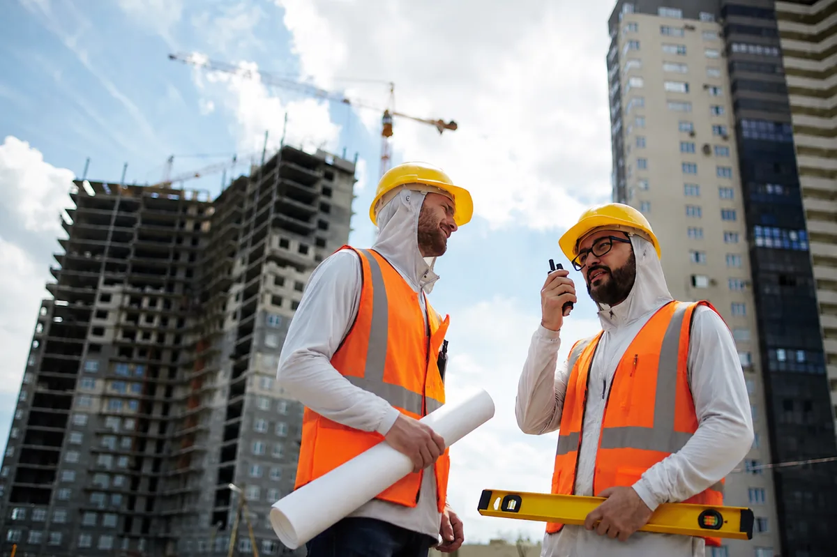 Construction supervisors wearing sun hoodies and reflective safety vests on a U.S. building site
